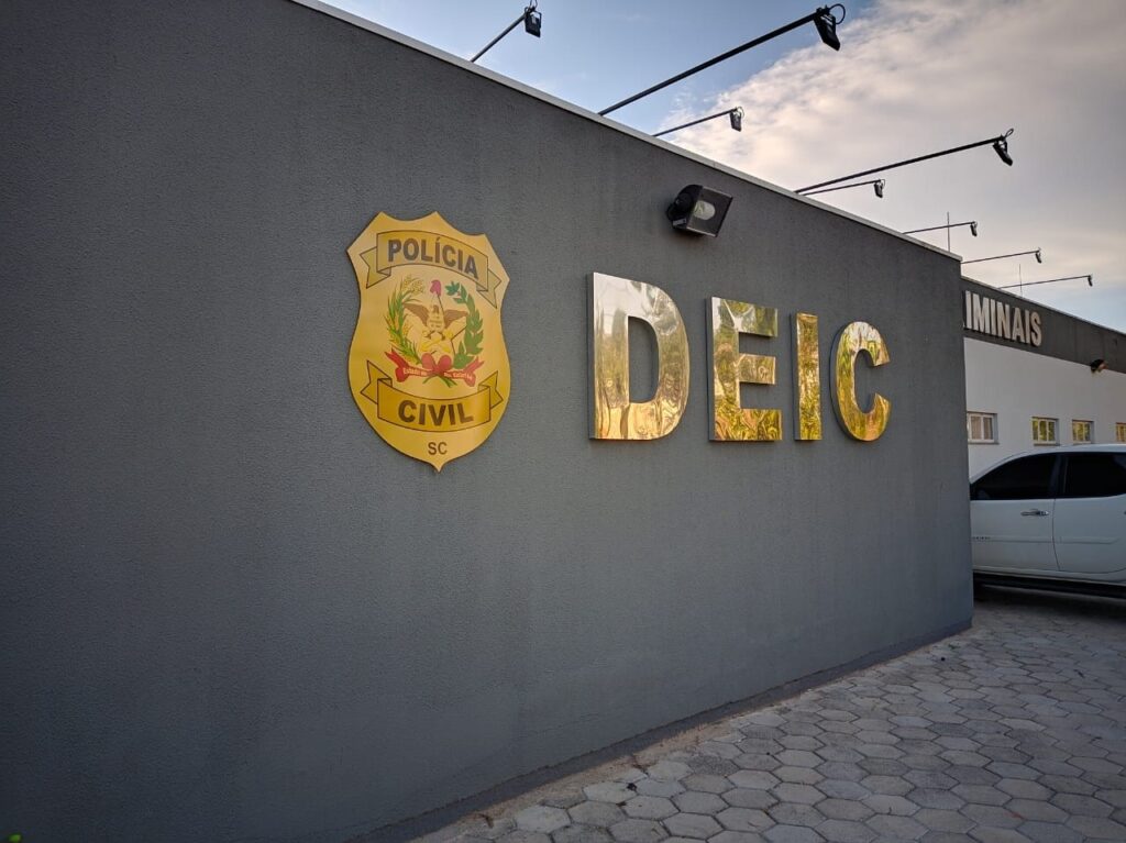parede cinza com o símbolo da policia civil e a palavra DEIC ambas em dourado