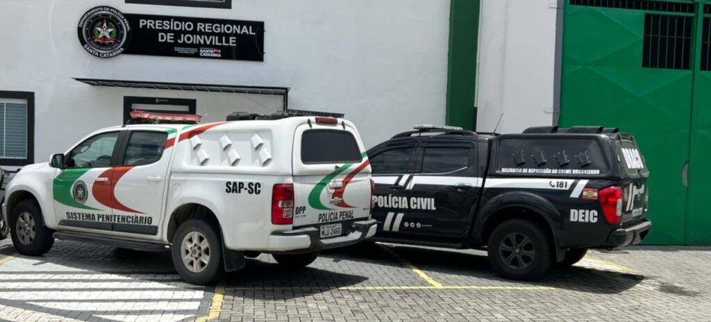 viatura estacionadas de forma lateral policia penal e civil da esquerda pra direita em frente do prédio do presidio regional de Joinville
