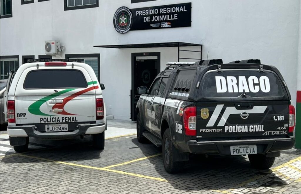 viatura policia civil no lado direito e viatura da policia penal no lado esquerdo, ambos em frente do prédio do presidio regional de Joinville
