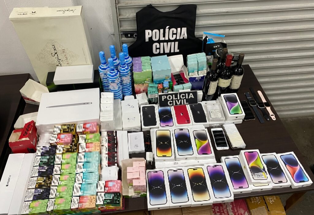 Colete da policia civil, celulares, vinhos e outros materiais sobre uma mesa