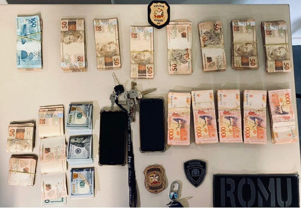 mesa com chave, celular e dinheiro junto com a insígnia da policia civil e da guarda municipal