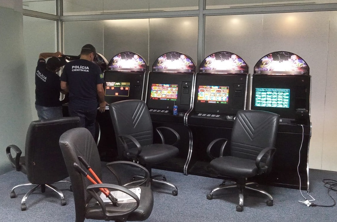 policiais da policia cientifica em frente a maquinas de jogos de azar