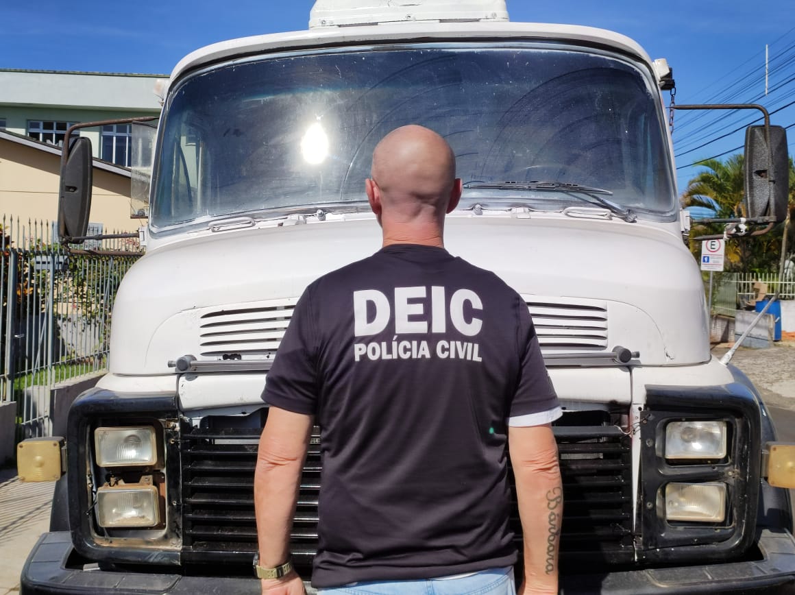 Policial civil da DEIC em frente de caminhão